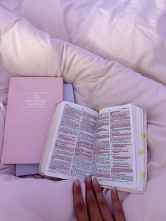 a person laying in bed with a book open on their lap and hand resting on top of the book