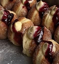 several pastries with jelly and powdered sugar are arranged on a silver counter top