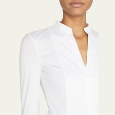 Akris punto blouse in cotton poplin, featuring a jersey back. Split neckline. Long sleeves. Hem hits hips. Fitted. Cotton. Made in Italy. Classic Tops For Workwear, Fitted Elastane Tops For Office, Modern Stretch Blouse For Workwear, Formal Long Sleeve Elastane Tops, Formal Fitted Top In Elastane, White Stretch Tops For Business Casual, Chic Elastane Workwear Blouse, Chic Elastane Blouse For Work, Modern Stretch Tops For Formal Occasions