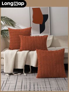 three orange and white pillows sitting on top of a couch next to a plant in a living room