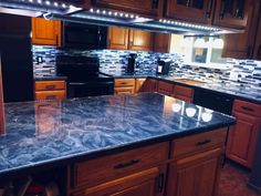 a kitchen with granite counter tops and wooden cabinets in the center, along with stainless steel appliances