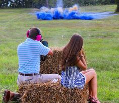 a man and woman sitting on top of a hay bale