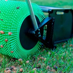 a green umbrella laying on top of grass next to a black object with holes in it