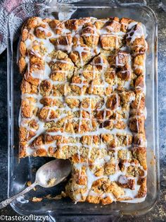 a pan filled with cinnamon rolls covered in white icing and drizzled