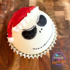 a frosted cupcake with a santa claus hat on it's head and eyes