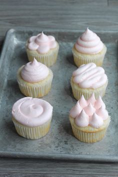 cupcakes with white frosting sitting on a tray