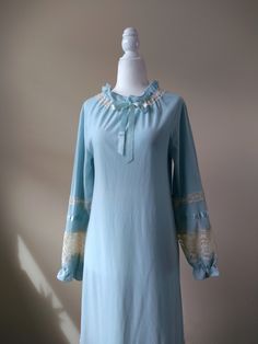 "Vintage sky blue fleece nightgown by Gossard Artemis. Features high ruffled neckline with center ribbon, ruffled cuffs, and lace and satin detailing throughout. Constructed from a warm fleece material. Era: Circa 1960s Condition: Excellent Size: Petite Color: Blue, ivory Brand: Gossard Artemis Measurements: 16in pit to pit, 23in sleeve length, 53in length Fabric Content: 100% nylon (body); 100% polyester (lace) Shown on a mannequin with a 33\" bust, 26\" waist, and 35\" hips. Fits a size 2-4. Model is 5'5 with a 34A bust. Some garments may be clipped onto mannequin or model for display. MORE INFO: *Please, note that all items are vintage. Therefore, it is expected to find some wear. Ariessence by Ariel is an admirer of fashion history and hopes you can appreciate this garment and its char Blue Long Sleeve Bedtime Dress, Blue Long Sleeve Dress For Pajama Party, Long Sleeve Blue Nightgown For Sleepover, Blue Long Sleeve Nightgown For Sleepover, Feminine Blue Sleepwear For Pajama Party, Long Sleeve Ruffled Nightgown For Loungewear, Blue Lace Trim Coquette Dress, Blue Long Sleeve Nightgown For Pajama Party, Light Blue Long Sleeve Loungewear Dress