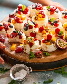 a person is decorating a fruit pizza on a wooden platter with fresh fruit