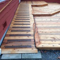 a wooden deck that has been built into the side of a red building with steps leading up to it