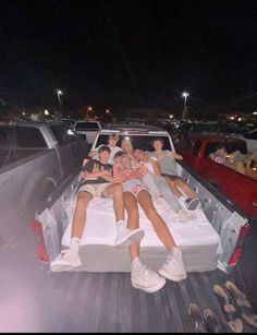 four people sitting in the back of a pick up truck