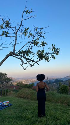 a woman standing under a tree in the grass