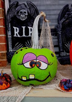 two pumpkins with faces painted on them sitting in front of a halloween sign and other decorations