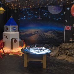 a space themed birthday party with rocket ship and rockets on the wall, lights in the background