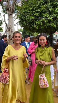 two women in yellow dresses are walking down the street with shopping bags and purses