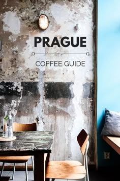 a table and chairs in front of a wall with the words prague coffee guide written on it