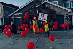 two clowns are standing in front of a house with red balloons and a free candy sign