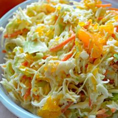 a bowl filled with coleslaw and carrots on top of a table