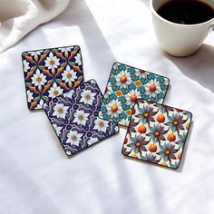 three coasters with colorful designs on them next to a cup of coffee