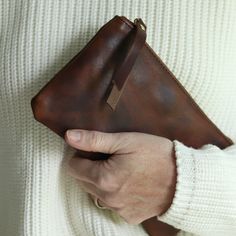 a person holding a brown leather pouch in their hand