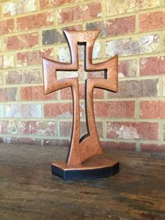 a wooden cross sitting on top of a table next to a brick wall and floor