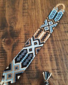 a blue and white beaded tie sitting on top of a wooden table next to two tassels