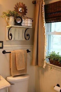 a white toilet sitting next to a window in a bathroom under a sunflower decoration