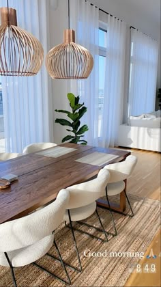 a dining room table with white chairs and hanging lights