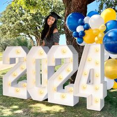 a woman standing next to a large sign with balloons in the shape of letters and numbers