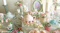 a table topped with lots of plates covered in cakes and cupcakes next to candles