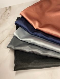 four different colors of satin fabric stacked on top of each other in various sizes and shapes