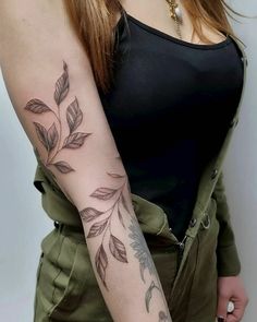 a woman's arm with leaves on it and a tattoo design on the arm