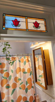 a bathroom with two stained glass windows above the sink and shower curtain in front of it