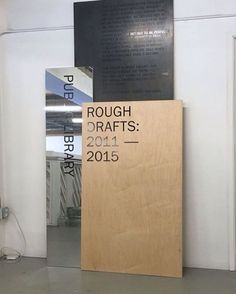 a wooden sign sitting on top of a floor next to a white wall and door