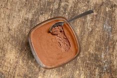 a spoon full of chocolate powder on top of a wooden table