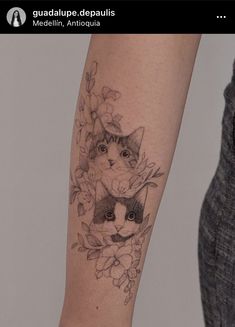 a woman's arm with a cat and flowers tattoo on the left side of her arm