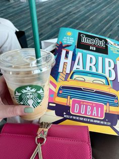 a person holding a starbucks drink and a book