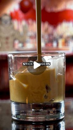 a glass filled with liquid sitting on top of a table next to a wooden stick