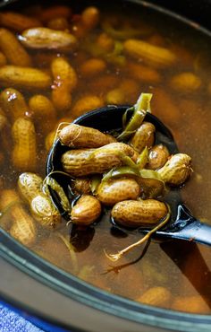 a spoon full of food sitting on top of a pot filled with broth and beans