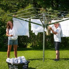 a man and woman standing in the grass next to clothes drying on a clothes line