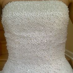 the back of a white wedding dress with lots of beading on it's bust