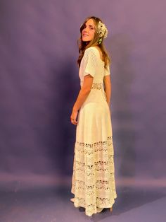 a woman in a white dress is standing against a purple background with her back to the camera