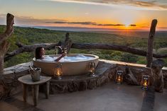 a woman taking a bath in a large outdoor jacuzzi tub with candles around it