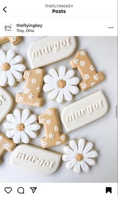 decorated cookies are arranged in the shape of numbers and daisies on a white surface