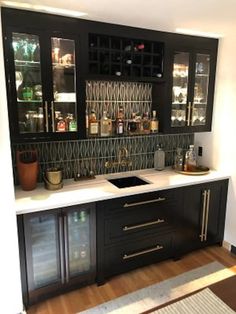 a kitchen with black cabinets and white counter tops is seen in this image, there are wine glasses on the shelves above the sink