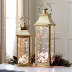 two gold lanterns with christmas decorations on them