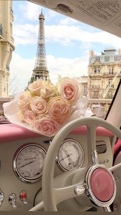 a pink car with flowers on the dashboard and eiffel tower in the background