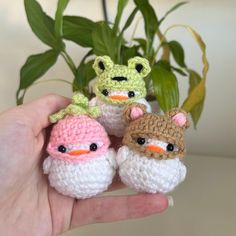 three small crocheted birds sitting on top of each other in front of a potted plant