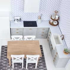 an aerial view of a kitchen and dining area with white chairs, counter tops, cabinets, and rugs