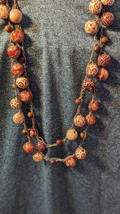 Embrace the spirit of bohemia with this exquisitely handcrafted crochet necklace, adorned with bold wooden beads that make a statement. Each bead is intricately designed, boasting unique patterns and rich, earthy tones that will add a touch of rustic elegance to any outfit. The comfortable crochet cord lays softly against your skin, making it perfect for all-day wear. Whether you're dressing up for a festival or accenting your daily attire, this boho necklace is versatile enough to be your go-to Bohemian Fair Trade Adjustable Beads, Traditional Macrame Necklaces For Festivals, Natural Bohemian Jewelry With Wooden Beads, Traditional Wooden Beads Jewelry For Beach, Bohemian Natural Wooden Beads Jewelry, Bohemian Fair Trade Beaded Necklaces For Festival, Bohemian Jewelry With Wooden Beads In Natural Color, Bohemian Ethical Beaded Necklaces For Festivals, Earthy Macrame Necklaces For Festivals