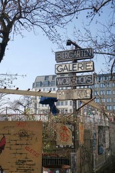 several street signs on top of each other in front of a building and trees with no leaves